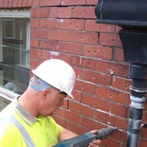 A man in a hard hat and safety vest working on a pipe.